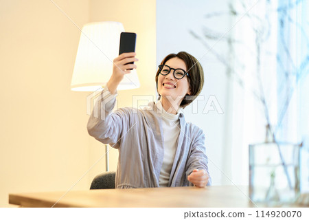 A woman holding a smartphone in a room A woman holding a smartphone in a room 114920070