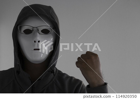 A man wearing a white mask and glasses clenching his fist 114920350