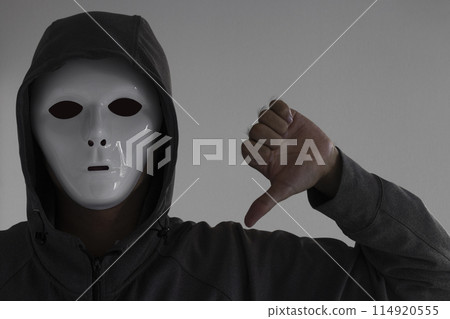 A man wearing a white mask giving a thumbs down A man wearing a white mask giving a thumbs down 114920555