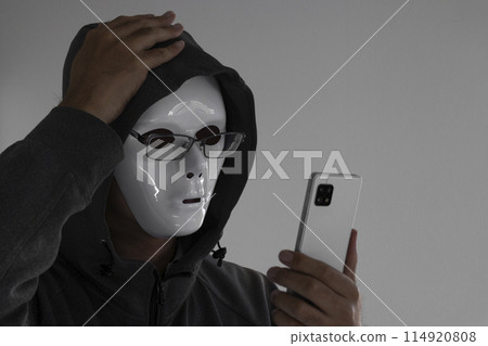 A man wearing a white mask and glasses holding a smartphone. He holds his head A man wearing a white mask and glasses holding a smartphone. He holds his head 114920808