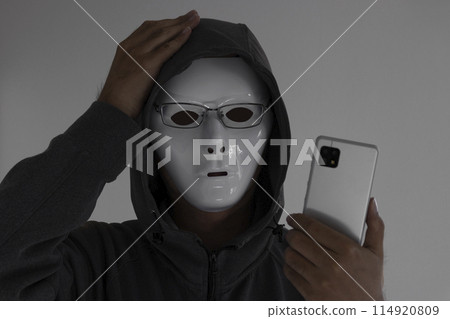 A man wearing a white mask and glasses holding a smartphone. He holds his head 114920809