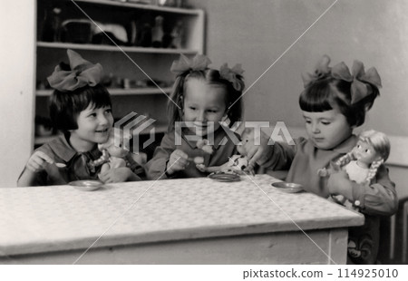 USSR, Circa 1972. Cute girls play with dolls in kindergarten. USSR, Circa 1972. Cute girls play with dolls in kindergarten. 114925010