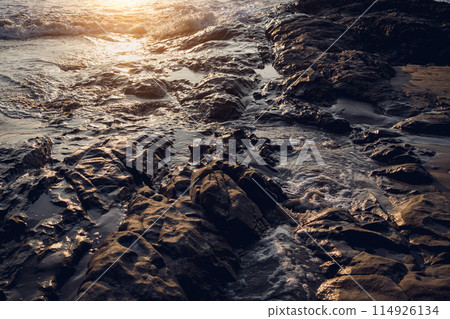 A large rocks surrounded by waves of the ocean A large rocks surrounded by waves of the ocean 114926134