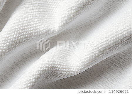 A close-up of a white knitted fabric. The knit has a waffle pattern and the fabric is soft and fluffy. 114926651