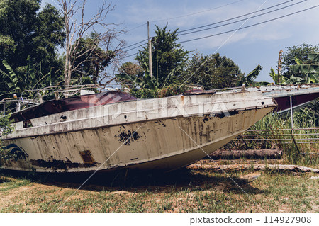 Old and rusty motor boats on a landfill surrounded by tropical forest 114927908