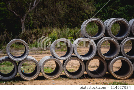 A stack of concrete ring pipes piled and creating a symmetrical arrangement A stack of concrete ring pipes piled and creating a symmetrical arrangement 114927924