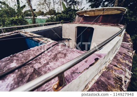 Old and rusty motor boats on a landfill surrounded by tropical forest Old and rusty motor boats on a landfill surrounded by tropical forest 114927948