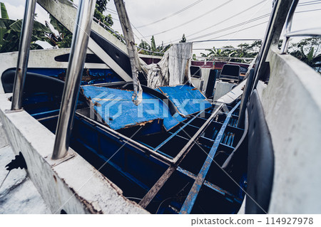 Old and rusty motor boats on a landfill surrounded by tropical forest 114927978