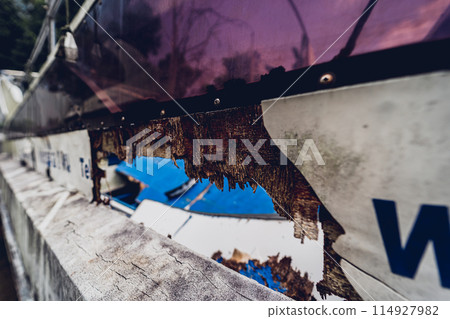 Old and rusty motor boats on a landfill surrounded by tropical forest 114927982