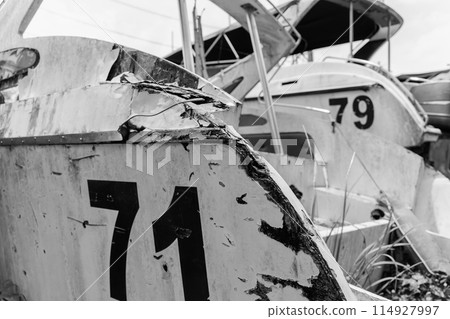 Old and rusty motor boats on a landfill surrounded by tropical forest 114927997