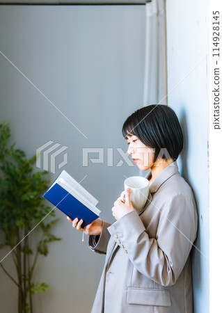 一位女士站著閱讀/重新學習技能 一位女士站著閱讀/重新學習技能 114928145