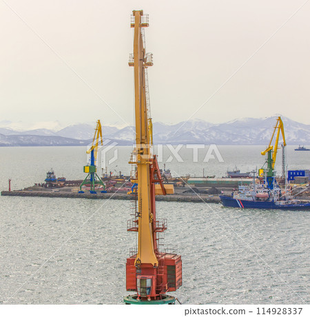 Port cranes and ships on commercial seaport Petropavlovsk-Kamchatsky City on shore of Avacha Bay in Pacific Ocean. Port cranes and ships on commercial seaport Petropavlovsk-Kamchatsky City on shore of Avacha Bay in Pacific Ocean. 114928337