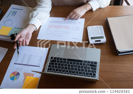 Cropped image of professional businesswoman, entrepreneur or accountant working on a financial report paperwork at her desk, using calculator or laptop. Cropped image of professional businesswoman, entrepreneur or accountant working on a financial report paperwork at her desk, using calculator or laptop. 114928381