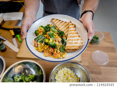 Chef at the kitchen preparing tofu scramble with vegetables Chef at the kitchen preparing tofu scramble with vegetables 114928585