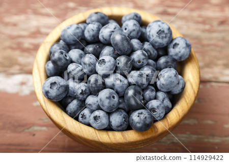 Blueberry berries are in a wooden plate on wooden background. Healthy food and healthy lifestyle. 114929422
