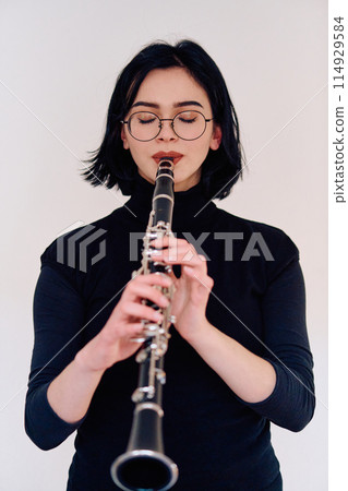 Graceful Brunette Musician Posing with Clarinet on White Background 114929584