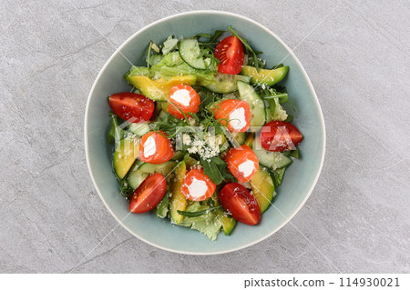 Salmon salad with green leaves, avocado and tomato on black stone background. Top view with copy space. 114930021