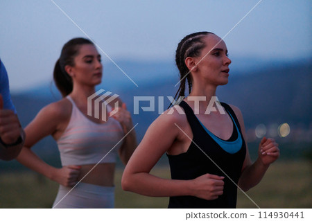 A diverse group of runners trains together at sunset. A diverse group of runners trains together at sunset. 114930441