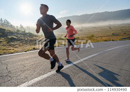 Energized by the beauty of nature, a couple powers through their morning run, their bodies and spirits invigorated. Energized by the beauty of nature, a couple powers through their morning run, their bodies and spirits invigorated. 114930490
