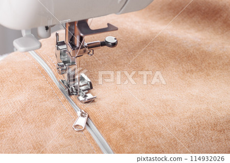 Modern sewing machine special presser foot with beige fabric and zipper, closeup Modern sewing machine special presser foot with beige fabric and zipper, closeup 114932026