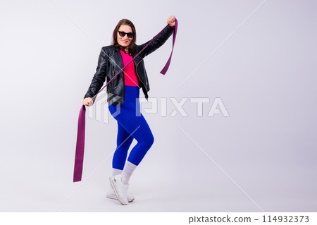 Strong female working with resistance band. Model in fashionable sportswear, grey background. Strong female working with resistance band. Model in fashionable sportswear, grey background. 114932373