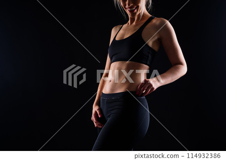 Middle aged woman doing fitness workout, standing in activewear with abs and muscles, smiling happy 114932386