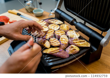 Chef at the kitchen preparing grilled eggplants with garlic Chef at the kitchen preparing grilled eggplants with garlic 114932759
