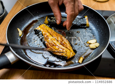 Chef at the kitchen preparing grilled eggplants with garlic Chef at the kitchen preparing grilled eggplants with garlic 114932886