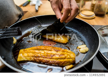 Chef at the kitchen preparing grilled eggplants with garlic Chef at the kitchen preparing grilled eggplants with garlic 114932891