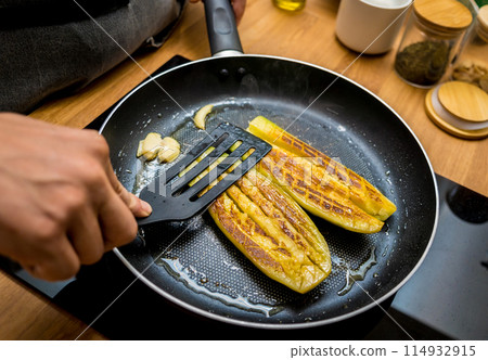 Chef at the kitchen preparing grilled eggplants with garlic 114932915