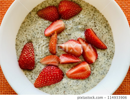 A lot of healthy Chia pudding with coconut milk in a white plate with fresh pieces strawberry. Close-up A lot of healthy Chia pudding with coconut milk in a white plate with fresh pieces strawberry. Close-up 114933906