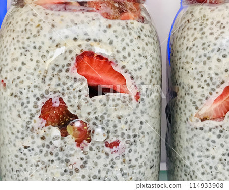 A lot of healthy Chia pudding with coconut milk in a glass containers can with fresh pieces strawberry, raspberry in the refrigerator on the shelf. Close-up A lot of healthy Chia pudding with coconut milk in a glass containers can with fresh pieces strawberry, raspberry in the refrigerator on the shelf. Close-up 114933908