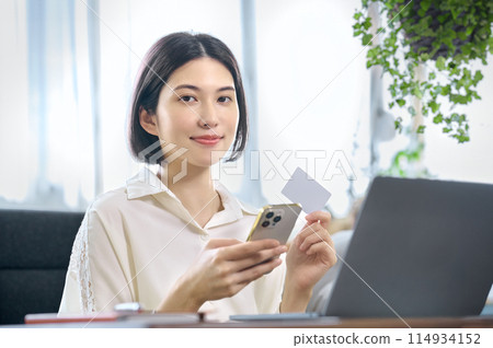 A young woman who makes cashless payments using a computer 114934152