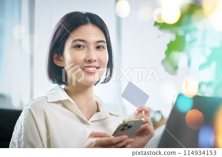 一個使用計算機進行無現金付款的年輕女子 一個使用計算機進行無現金付款的年輕女子 114934153