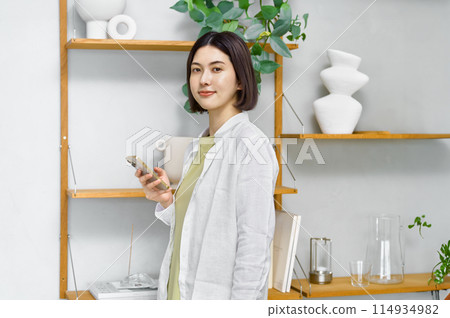 一位年輕女子在房間裡看著她的智慧型手機 114934982