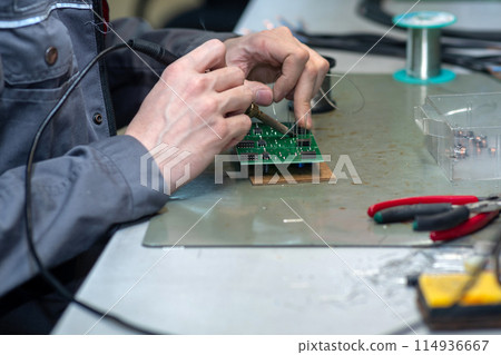worker`s hand soldering of electronic circuit boards close-up worker`s hand soldering of electronic circuit boards close-up 114936667