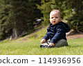 Baby boy playing outside on green grass in lush Canadian Nature. 114936956