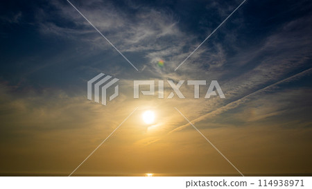 The setting sun and flowing clouds in the evening sky 114938971