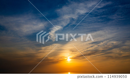 The setting sun and flowing clouds in the evening sky 114939050