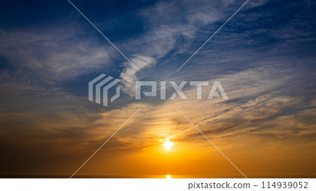 The setting sun and flowing clouds in the evening sky 114939052