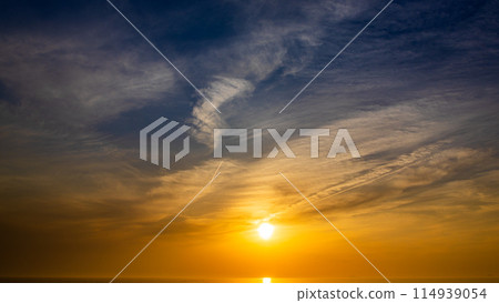 The setting sun and flowing clouds in the evening sky 114939054