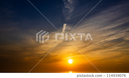 The setting sun and flowing clouds in the evening sky 114939076