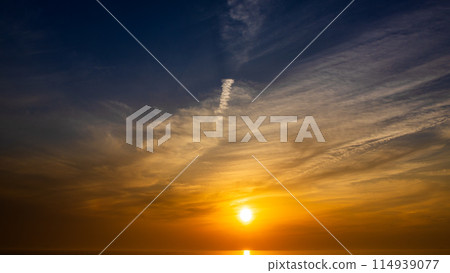 The setting sun and flowing clouds in the evening sky 114939077