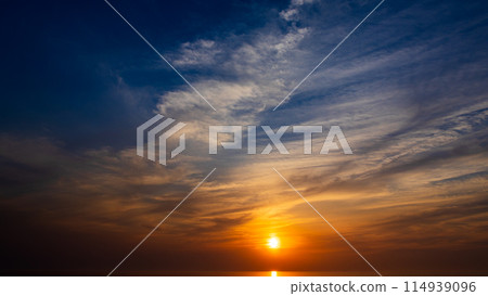 The setting sun and flowing clouds in the evening sky The setting sun and flowing clouds in the evening sky 114939096