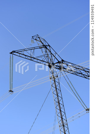 The construction of a high-voltage power line in close-up. Wires on a blue sky background. 114939491