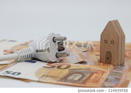 White electric cable and banknotes against the background of a toy model house 114939588