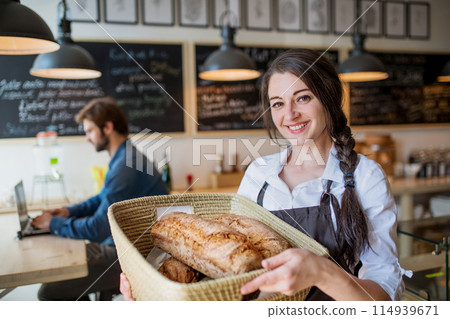 Homemade bread in small bakery. Woman holding basket with various bread freshly baked. Close up Homemade bread in small bakery. Woman holding basket with various bread freshly baked. Close up 114939671
