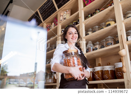 Shop assistant working in package-free store using reusable containers. Zero waste shops offering package-free bulk goods and sustainable alternatives. Shop assistant working in package-free store using reusable containers. Zero waste shops offering package-free bulk goods and sustainable alternatives. 114939672