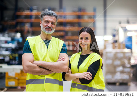 Warehouse employees in warehouse. Two workers in reflective clothing in modern industrial factory, heavy industry, manufactrury. 114939681