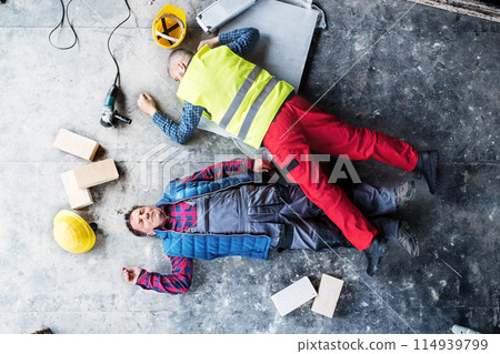Two unconscious man workers lying on the floor after a fall. Work injury, accident in workplace. 114939799